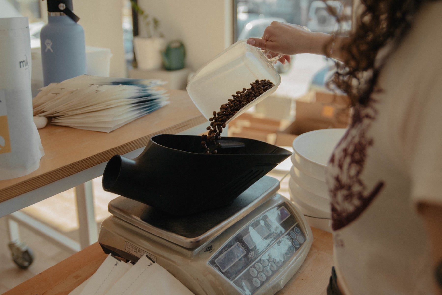 A person weighing roasted coffee beans at Mikko Roastery